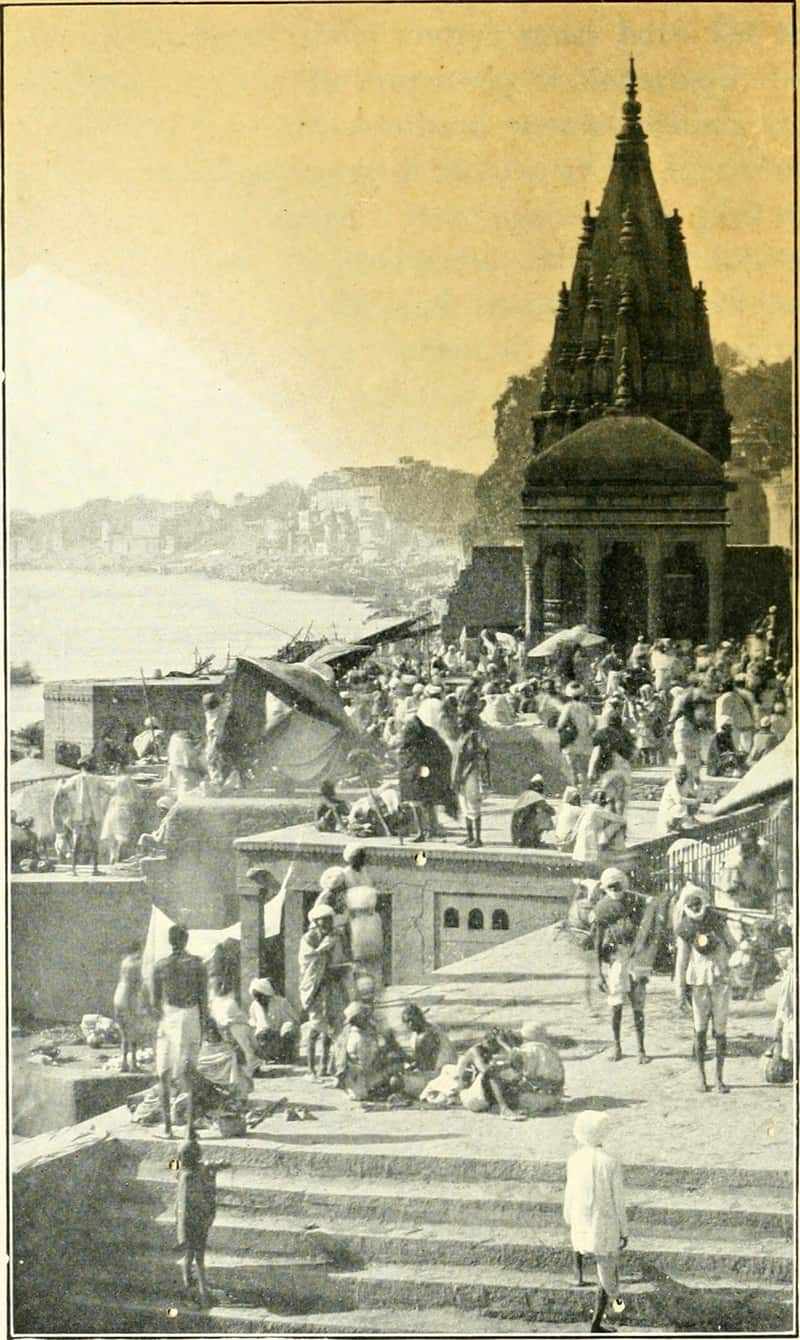 A sadhu with a danda staff seated on the ghat steps