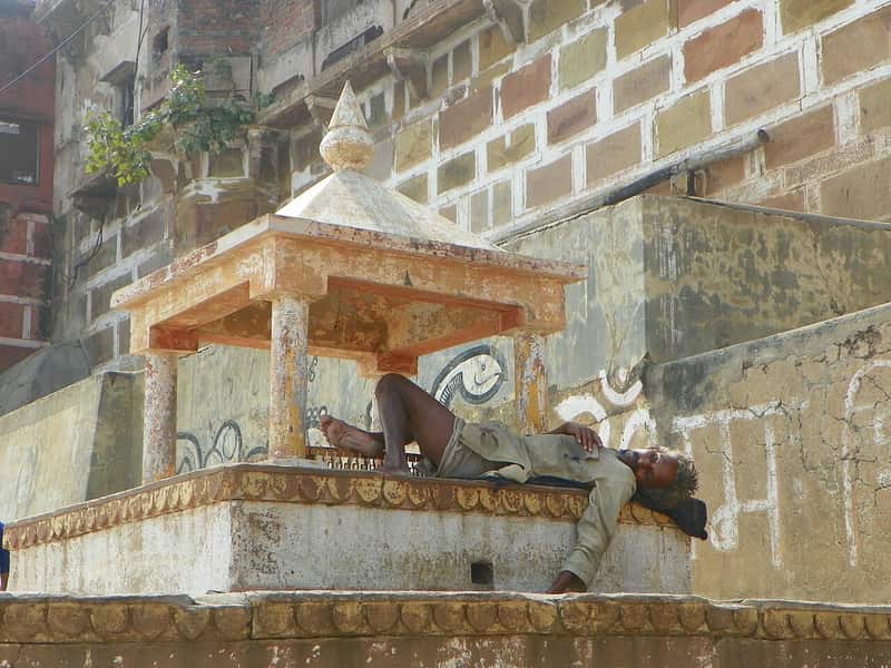 A sadhu in ochre robes giving blessings to pilgrims on the ghat
