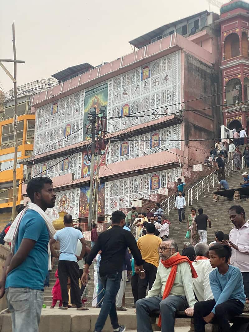 The ghat steps with pilgrims arriving through the morning lanes